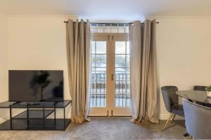 ein Wohnzimmer mit einem TV, einem Tisch und einem Fenster in der Unterkunft Lovely 2BED Whitehaven Apartment with Sea Views in Whitehaven + 26 Fotos