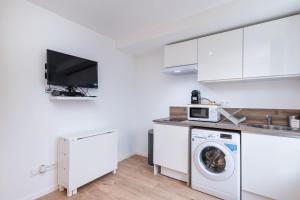 a white kitchen with a washing machine and a tv at Apartment Perron - Cozy 2 people - Oullins in Oullins +15 photos