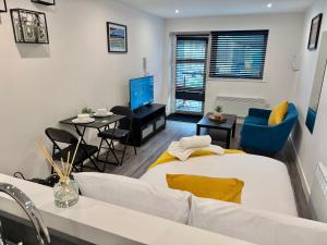 Sala de estar con cama, mesa y TV en Seaside Escape - Central Studio Near Beach and Town, en Bournemouth