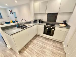 Una cocina con gabinetes blancos y electrodomésticos de acero inoxidable. en Seaside Escape - Central Studio Near Beach and Town, en Bournemouth