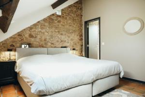Un dormitorio con una cama blanca y una pared de piedra. en Mariomont-La Terrasse du Pré, en Verviers