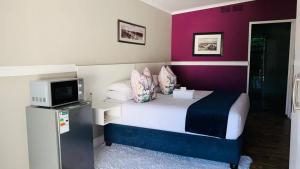 a bedroom with a bed with a tv and purple walls at Hidden Villas Guesthouse in East London