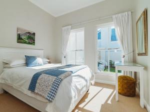 a white bedroom with a bed and a window at Trafford Cottage on Kingswood Golf Estate in George