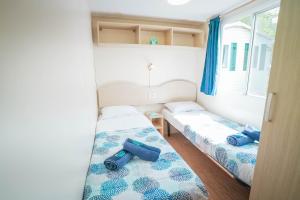 two beds in a small room with blue curtains at Happy Camp mobile homes in Camping Village Free Time in Marina di Bibbona +29 photos