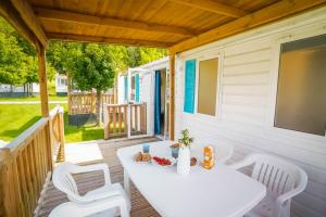 a white table and chairs on the porch of a tiny house at Happy Camp mobile homes in Camping Village Free Time in Marina di Bibbona