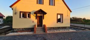 a small yellow house with a staircase leading to the door at Willa Wierzbiczany in Gniewkowo
