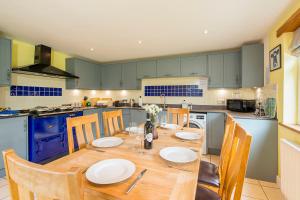 Swallows Rest في Croes-Gôch: مطبخ مع طاولة خشبية ودواليب زرقاء