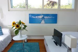 a living room with a computer and a vase of sunflowers at B&B Elegant in Ueberstorf