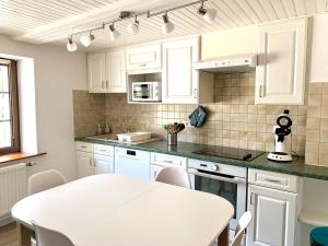 a kitchen with white cabinets and a white table at La Petite Lorraine in Bertrambois +7 photos