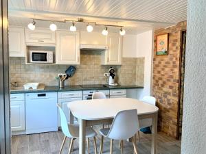 a kitchen with white cabinets and a table and chairs at La Petite Lorraine in Bertrambois