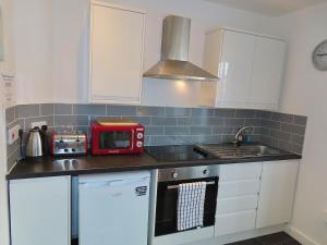 - une cuisine avec des placards blancs et un four micro-ondes rouge dans l'établissement 1 Double Bedroom Great Location - Holmfield Road, à Blackpool 5 autres photos