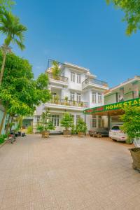 a large white building with trees in front of it at Nhat Long Homestay in Hue