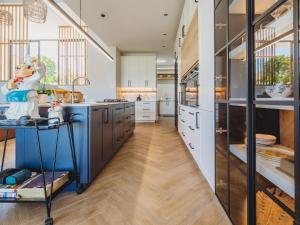 a large kitchen with a blue island and wooden floors at Fairbourne's View, Kingswood Golf Estate George in George +15 photos