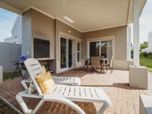 a patio with two white chairs and a television at Manor One Kingswood Golf Estate in George