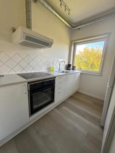 a white kitchen with a sink and a window at Dejlig 2 værelses lejlighed in Randers