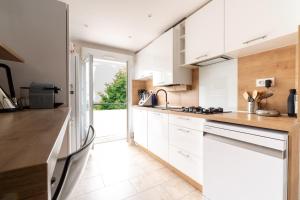 3 chambres lumineux proche gare et TNB في رين: مطبخ مع خزائن بيضاء وقمم منضدة خشبية