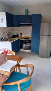 a kitchen with blue cabinets and a table and chairs at Bungalow Le Petit Havre Pointois in Basse-Pointe