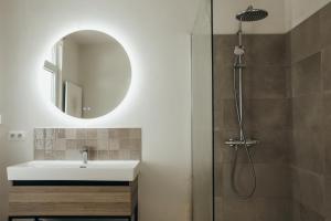 a bathroom with a sink and a shower with a mirror at La Terrasse des Guillemins by WelcHome in Liège