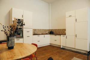 a kitchen with white cabinets and a wooden table at La Terrasse des Guillemins by WelcHome in Liège