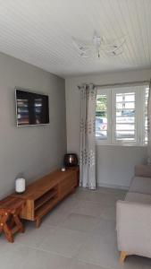 a living room with a couch and a tv at Bungalow Le Petit Havre Pointois in Basse-Pointe