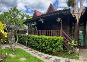 a house with a wooden fence and a yard at เรือนแฝด Brook view in Pai