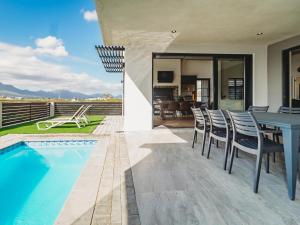 a patio with a table and chairs next to a swimming pool at 40 Ridge Drive, Kingswood Golf Estate in George