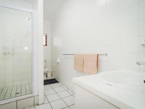 a white bathroom with a shower and a sink at Beachfront property, Victoria Bay, Garden route in Victoria Bay +13 photos