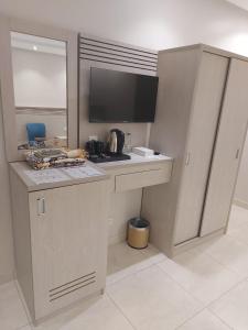 a kitchen with a counter with a stove and a tv at Orvana Al Naseem Hotel in Makkah