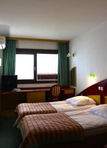 two beds in a hotel room with green curtains at MC Hotel in Žalec