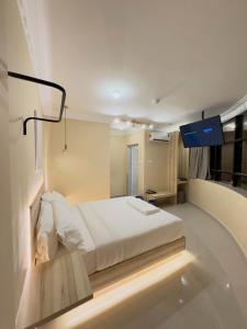 een slaapkamer met een wit bed en een blauw licht bij Blenz Hotel in Serdang
