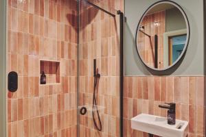 a bathroom with a shower with a sink and a mirror at Hay Barn in Trefeglwys