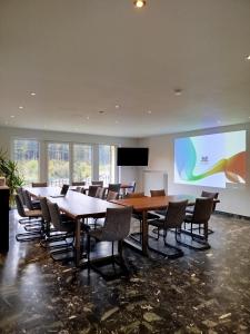 a conference room with tables and chairs and a screen at Whirlpool, Billiard, Sauna! Ferienhaus Lacher in Baiersbronn