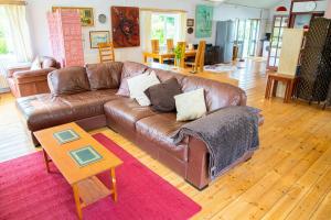 a living room with a brown leather couch and a table at Y Beudy at Coed Melin Aberporth in Tremain +16 photos