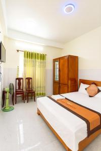 a bedroom with two beds and a tv and chairs at Hưng Phát Hotel Phú Yên in Phu Yen