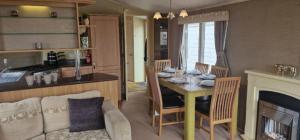 Una cocina y una sala de estar con una mesa y un sofá. en Lovely 8 Berth Caravan With Large Decking At Withernsea Sands Ref 79005Kg, en Waxholme