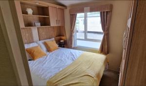 Un dormitorio con una cama blanca con una ventana. en Lovely 8 Berth Caravan With Large Decking At Withernsea Sands Ref 79005Kg, en Waxholme