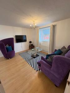 - un salon avec deux chaises violettes et une table dans l'établissement The Apartment, à Northallerton