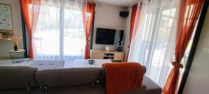 a living room with a couch and a table and windows at Havre de paix en Drôme villa moderne climatisée - jacuzzi "la maison d'à côté" in Chatuzange-le-Goubet