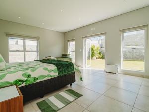 a bedroom with a bed and large windows at Knights Retreat on Kingswood Golf Estate in George