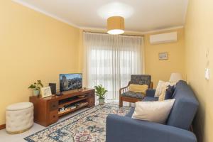 セトゥーバルにあるCoast 2 Bedroom Apart Setúbal 45 min from Lisbonの青いソファとテレビのあるリビングルーム