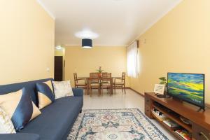 セトゥーバルにあるCoast 2 Bedroom Apart Setúbal 45 min from Lisbonの青いソファとテレビのあるリビングルーム