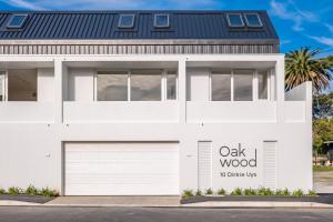 a white house with a oak wood sign on it at The Wild Oak in Hermanus