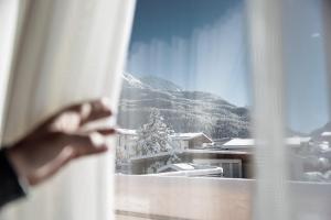 een persoon die uit een raam naar een besneeuwde berg kijkt bij MYALPS Ötztal inklusive Spa- Area in Umhausen
