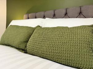 a bed with a green blanket and two pillows at Old Grey Mare in York