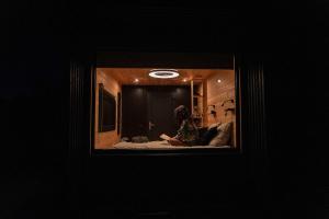a person sitting on a bed in a dark room at Homnest - Refuge en nature au coeur du Tarn in Puybegon