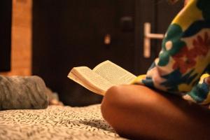 a child sitting on a bed reading a book at Homnest - Refuge en nature au coeur du Tarn in Puybegon