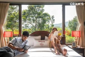 a man and a woman laying on a bed with a tablet at Gram's at Shivom, Pawna Lake in Lonavala
