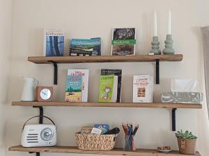 a shelf with books and a clock on it at Douce Parenthèse au bord de l'eau in La Celle-sous-Gouzon