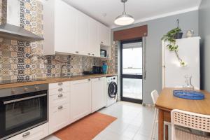 a kitchen with white cabinets and a wooden table at Coast 2 Bedroom Apart Setúbal 45 min from Lisbon in Setúbal