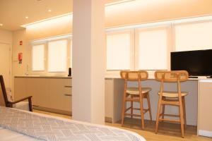 a kitchen with two stools and a counter with a television at ma-la studios Guimarães in Guimarães